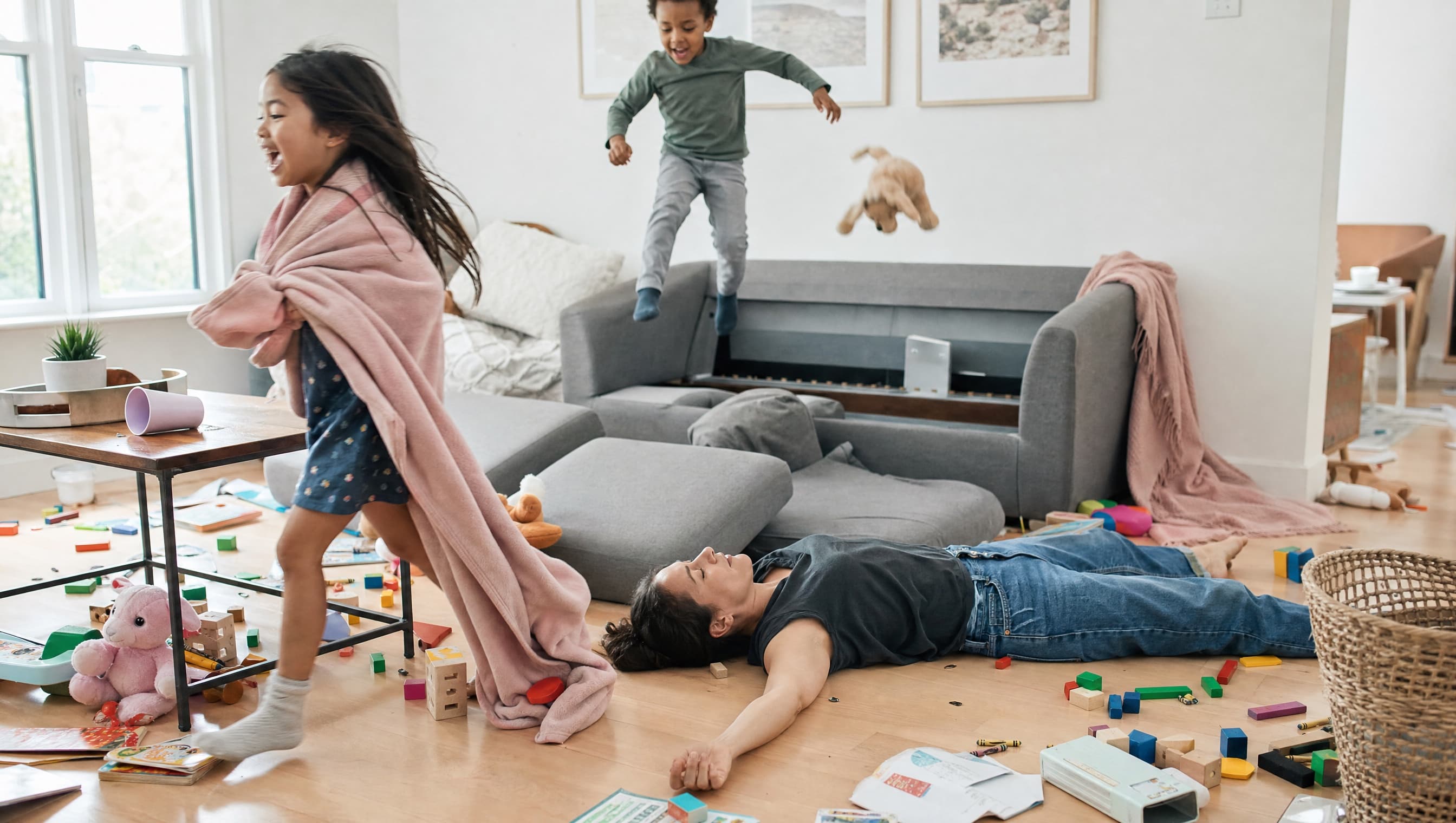A mum lying on the floor taking a minute while her kids play around her